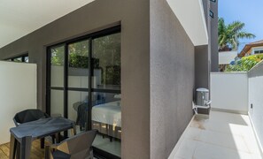 Ein Balkon mit Tisch und Stühlen, eine Schiebetür aus Glas und eine kleine Klimaanlage.