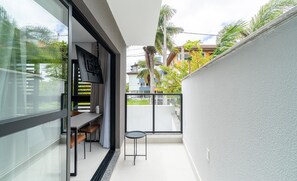 A balcony with a table and chairs, a small stool, and a view of neighboring buildings and trees. - Modern Studios 150m From Lagoa da Conceicao - Lsts II (Florianópolis)