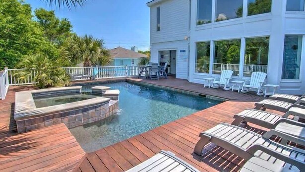 Uma área de piscina com hidromassagem, espreguiçadeiras e um deck.