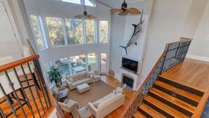 Uma sala de estar espaçosa com lareira, janelas amplas e vista para o exterior.