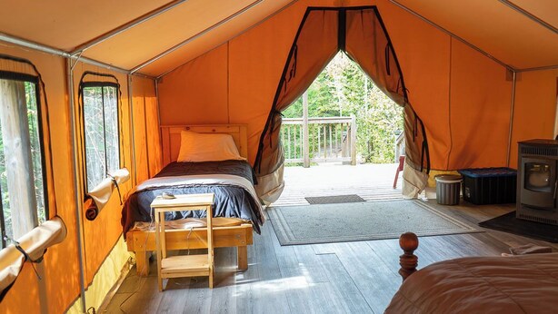 Eine Zelthütte mit Bett, kleinem Tisch, Heizung und Blick ins Freie.