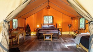 Ein Zelt mit einem Bett, einem Tisch und einem Stuhl.