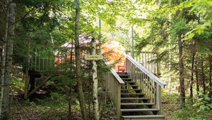 A wooden staircase leading up to a platform with a sign reading "GLAMPING 1".