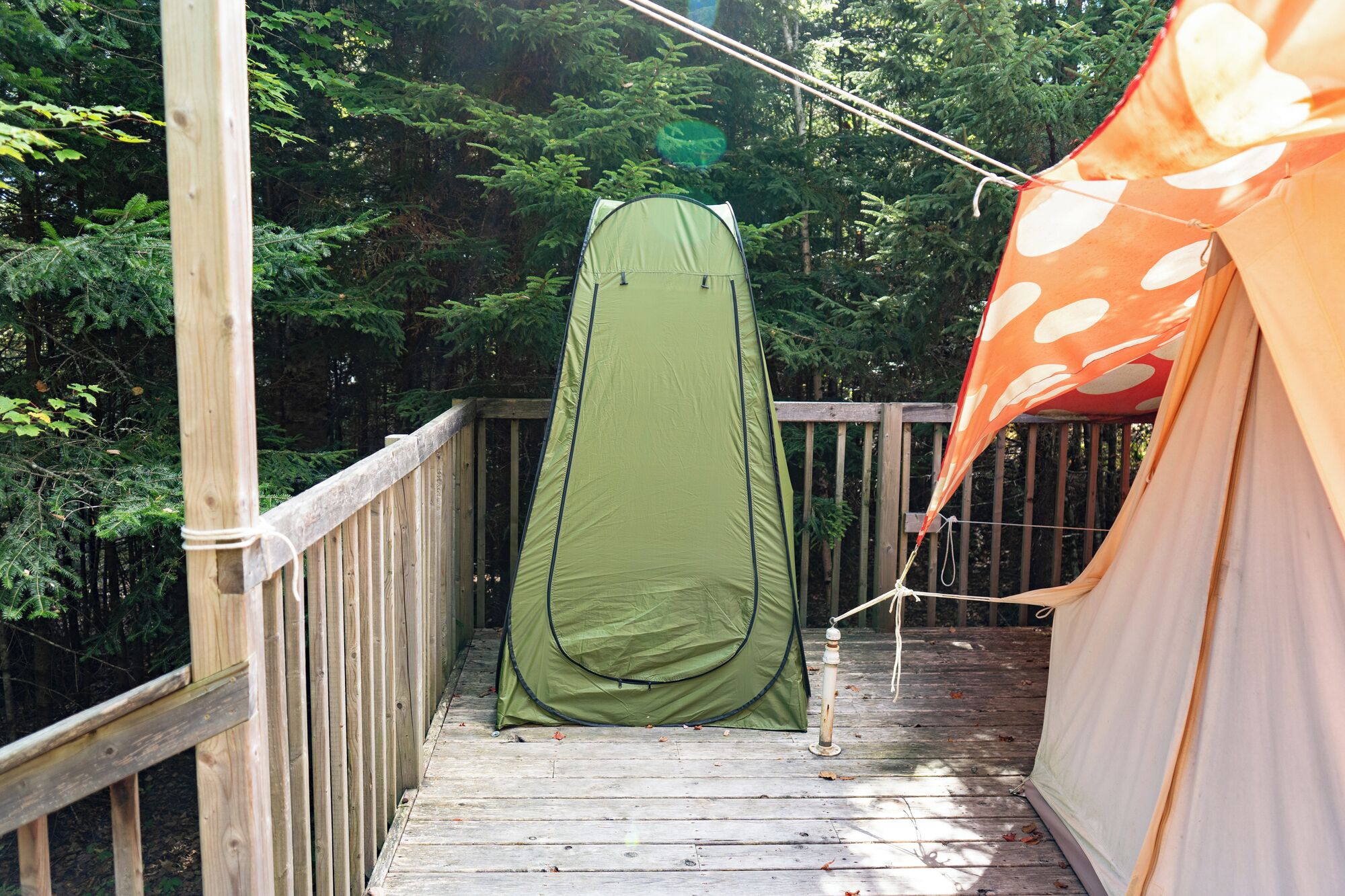 Un pontile di legno con una tenda verde e una tenda arancione.