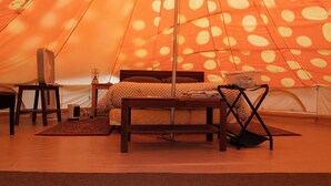Une tente équipée d’un lit, d’une chaise, d’une table et d’un ventilateur.