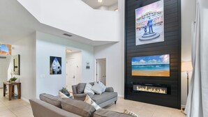 A spacious living room with a grey sectional sofa, a fireplace, and artwork on the walls. - Family Paradise - Theatre + Resort + Pet Friendly (Davenport)