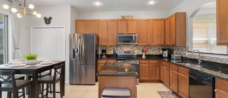 A modern kitchen with wooden cabinets, stainless steel appliances, and a granite countertop.