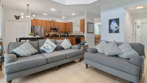 A modern kitchen with wooden cabinets, a stainless steel refrigerator, and a dining area with a table and chairs. - Family Paradise - Theatre + Resort + Pet Friendly (Davenport)