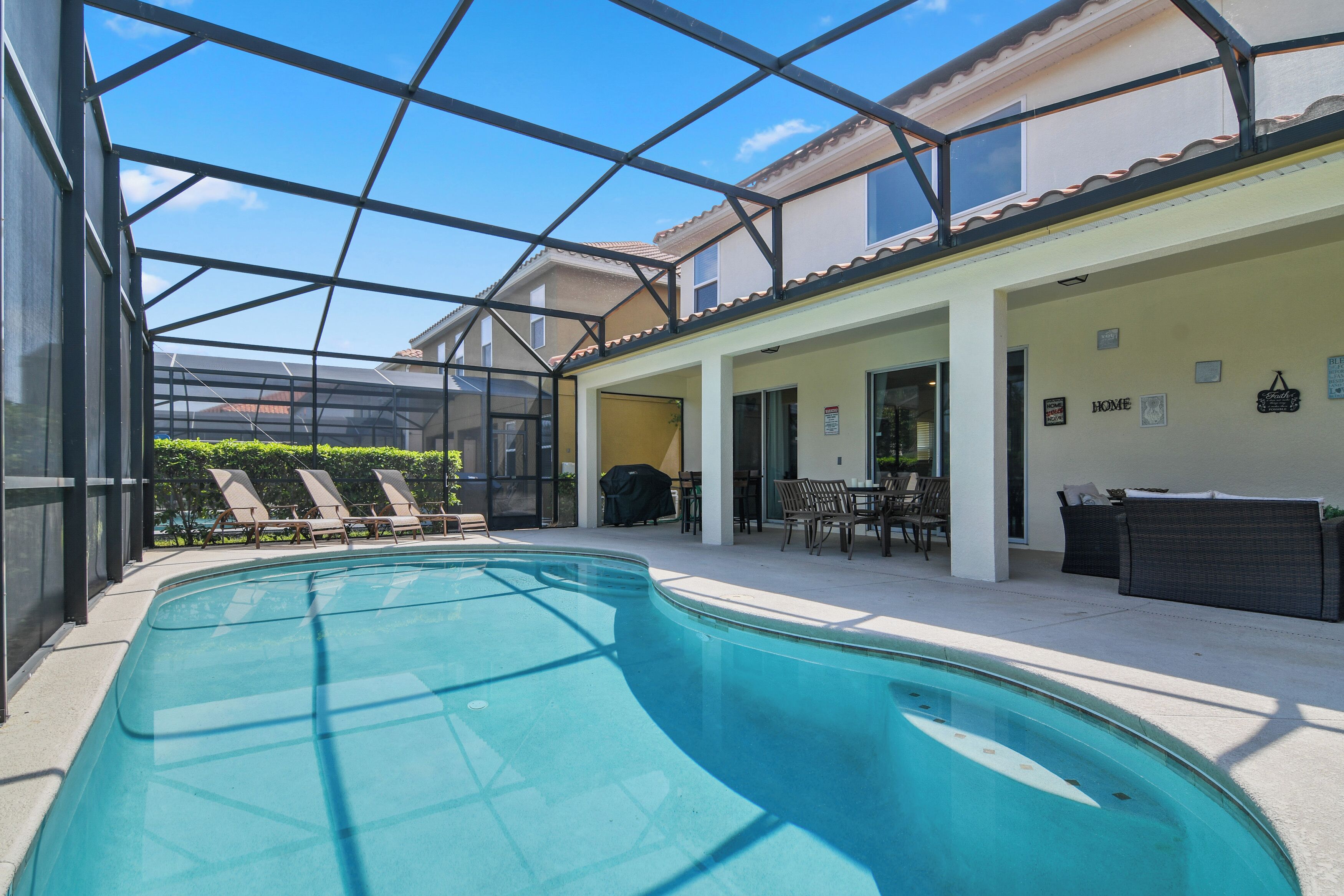 An indoor swimming pool with lounge chairs, a covered patio area, and a view of the surrounding buildings.