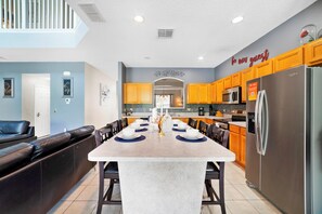A modern kitchen with a central island, wooden cabinets, and a stainless steel refrigerator. - Magical Paradise - Resort Home & In-door Arcade (Kissimmee)