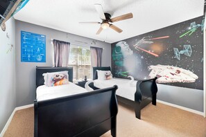 A bedroom with two black beds, a ceiling fan, a Star Wars-themed wall mural, and a window with blinds. - Magical Paradise - Resort Home & In-door Arcade (Kissimmee)