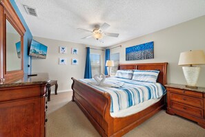 Ein Schlafzimmer mit einem hölzernen Bett, einem Deckenventilator, einem Fernseher und Kunstwerken an den Wänden.