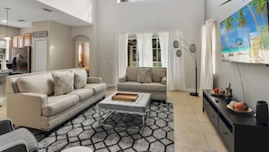 A spacious living area with a sofa, ottoman, and a dining table. - Villa Paradiso - South-facing Pool + Luxe Resort! (Kissimmee)