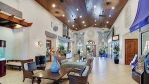 A spacious lobby with a high ceiling, wooden beams, and a central seating area with sofas and a coffee table. - Villa Paradiso - South-facing Pool + Luxe Resort! (Kissimmee)