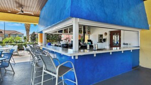 An outdoor bar area with a blue and yellow color scheme, a counter with a cash register, and metal chairs. - Villa Paradiso - South-facing Pool + Luxe Resort! (Kissimmee)