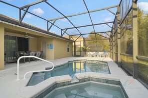 A swimming pool with a glass enclosure, a patio area with chairs, and a covered outdoor seating area. - Tranquil Terrace - 10 Mins to Disney! (Kissimmee)