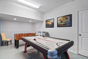 A pool table with a red and black design, a foosball table, and two framed posters on the wall. - Tranquil Terrace - 10 Mins to Disney! (Kissimmee)