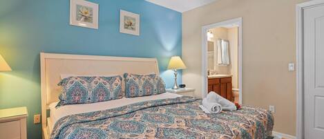 A bedroom with a bed, nightstands, a ceiling fan, and a bathroom visible through an open door.
