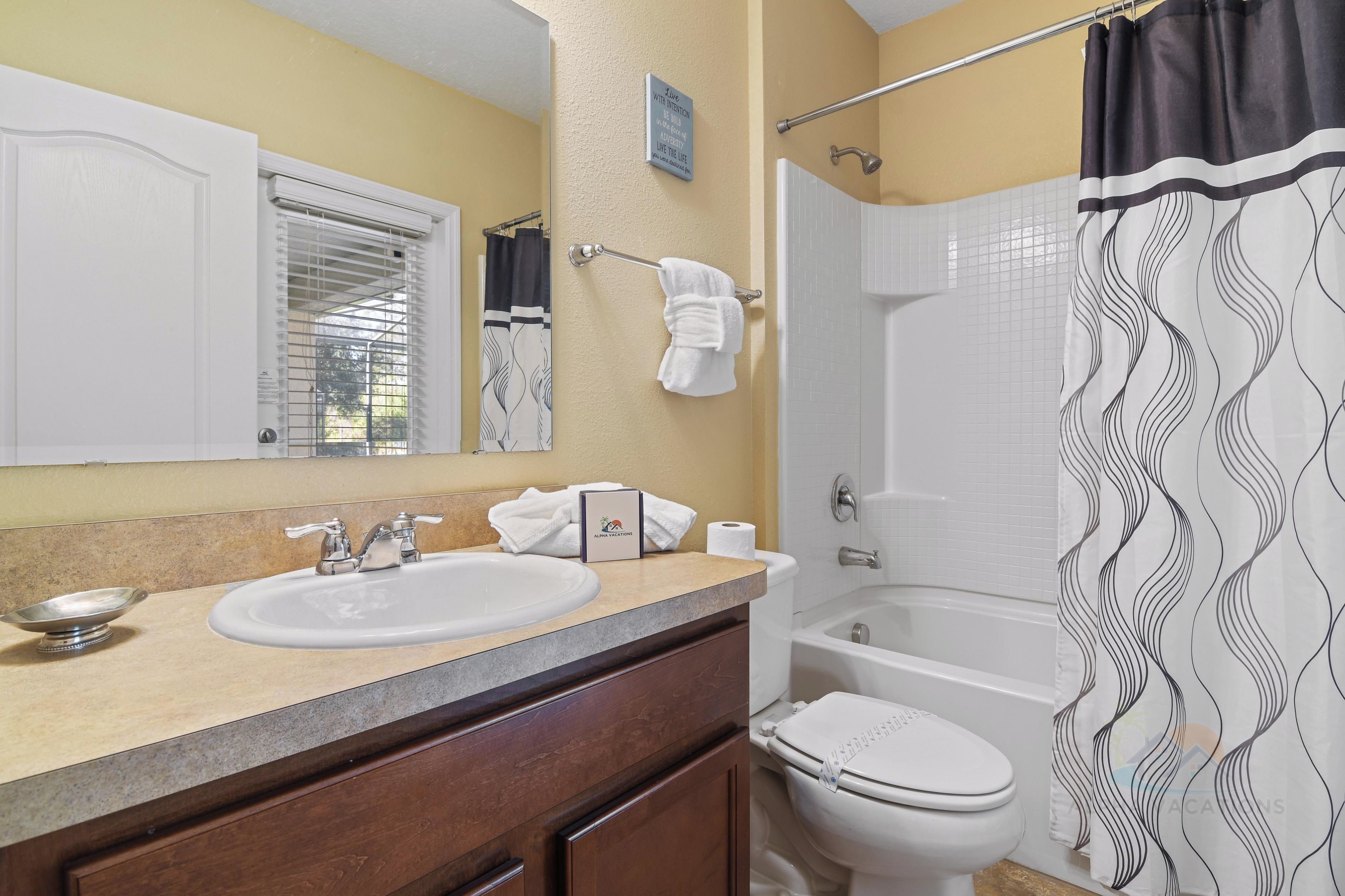 Une salle de bain équipée d’un lavabo, d’un miroir, d’un porte-serviettes et d’un rideau de douche.