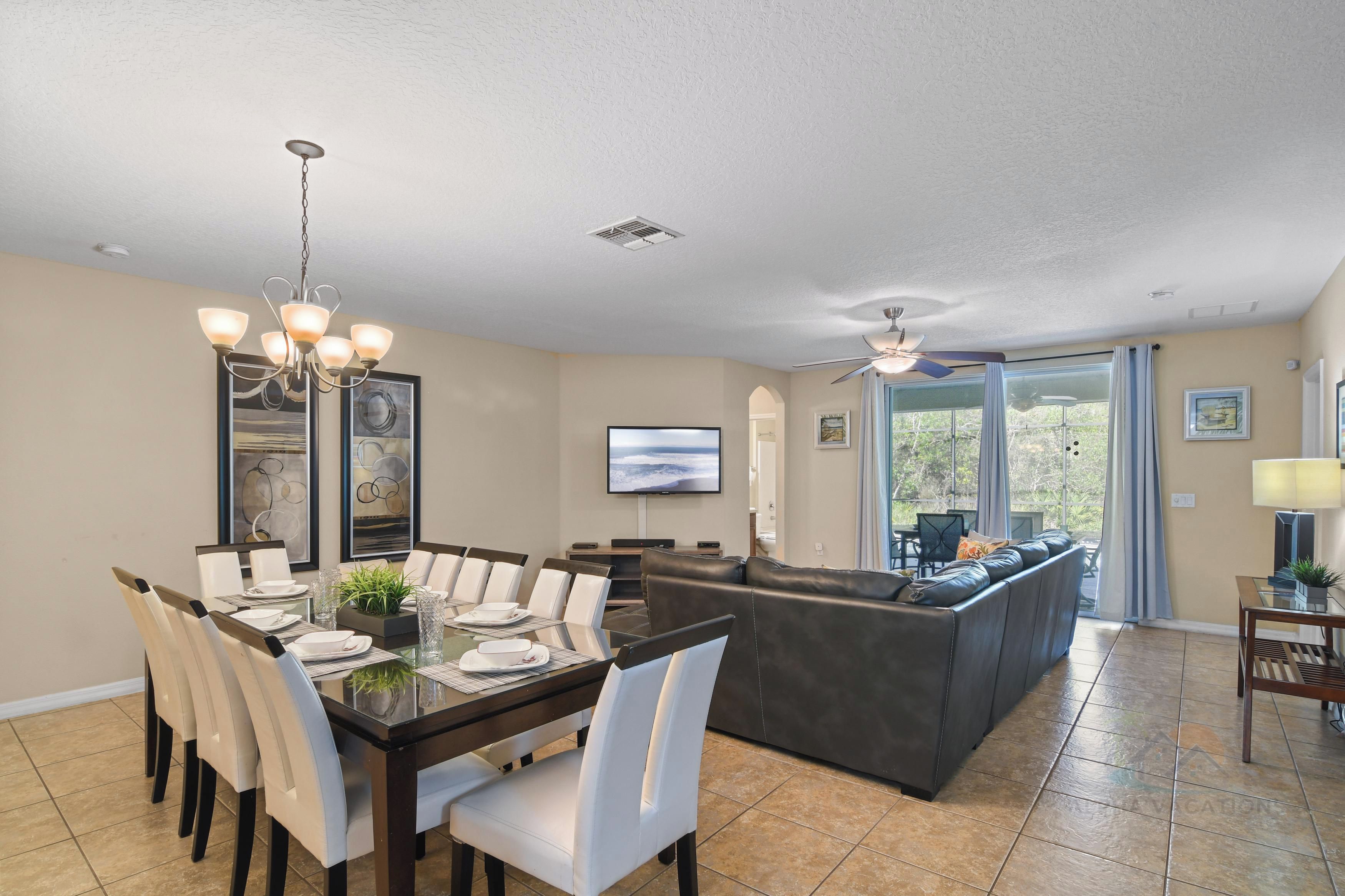 A spacious living area with a dining table, chairs, a sofa, and a TV.