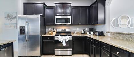 A modern kitchen with dark cabinets, stainless steel appliances, and a granite countertop.