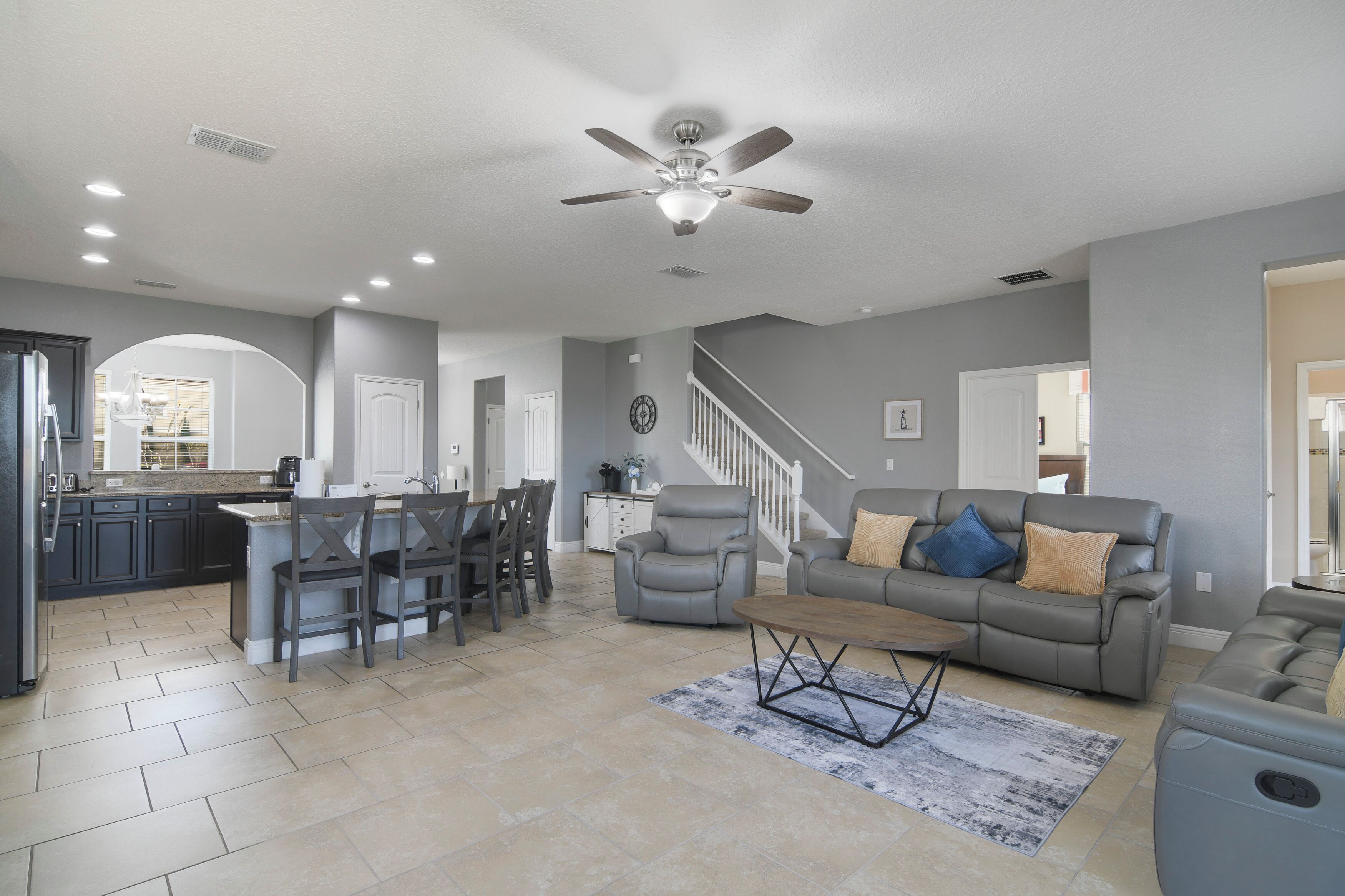 A spacious living room with a gray sofa, a coffee table, and a ceiling fan.