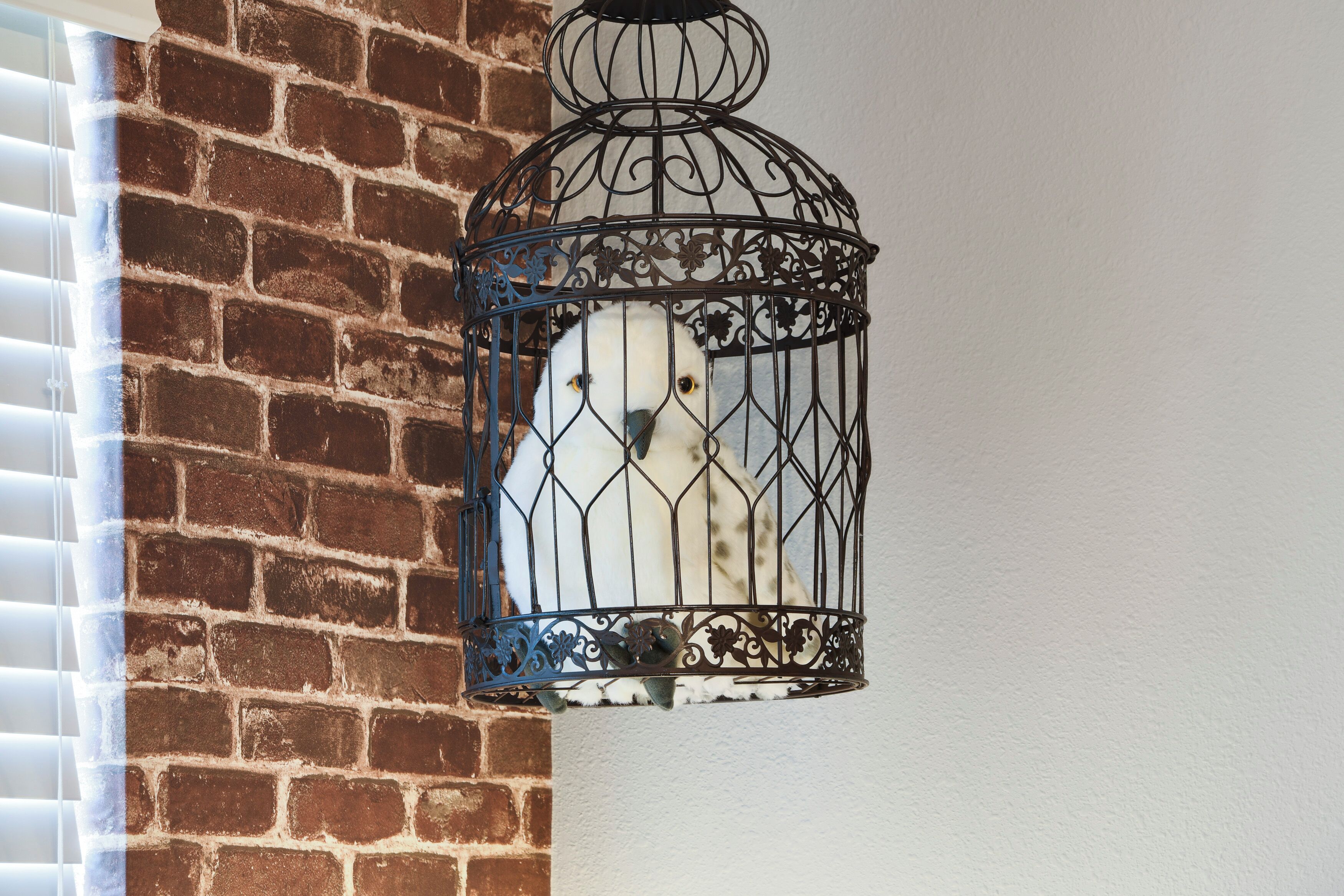 Une cage à oiseaux contenant un oiseau, fixée à un mur de briques.