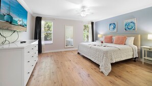 Une chambre à coucher avec un lit, une commode, un ventilateur de plafond et un tableau accroché au mur.