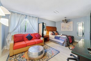 A bedroom with a red sofa, a bed with a swan pillow, a desk, and a large mirror. - The Farm House - Great Location + Pet Friendly! (Windermere)