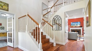 Un escalier avec des rampes blanches et des marches en bois menant à l’étage supérieur.