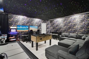 A room with a foosball table, two monitors, a sofa, and a cityscape wallpaper. - The Charming Chateau - Luxe - Resort - Location (Davenport)