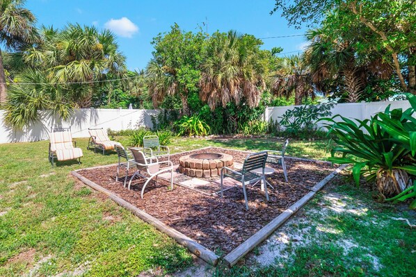 Un jardin avec un foyer, des sièges d’extérieur et une végétation luxuriante.