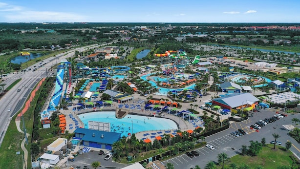 An aerial view of a water park with multiple pools, slides, and a large parking area. - Serenity - Family & Pet Friendly, Amazing Location (Kissimmee)