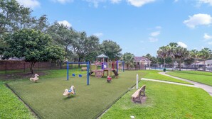 Ein Spielplatz mit Schaukeln, Klettergeräten und einem Pavillon.