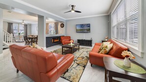 Ein modernes Wohnzimmer mit Ledersofas, einem Kamin und einem Essbereich mit Treppe.