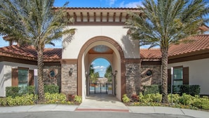A gated entrance with a stone archway, palm trees, and a clear blue sky. - Golden Getaway - Luxe Resort, Games & Views (Davenport)