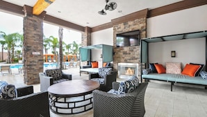 A spacious outdoor lounge area with wicker furniture, a stone fireplace, and a pool in the background. - Golden Getaway - Luxe Resort, Games & Views (Davenport)