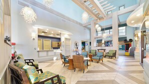 A spacious lobby with a high ceiling, modern furniture, and a central seating area. - Champions Oasis - Resort&arcade -walk to Clubhouse (Davenport)