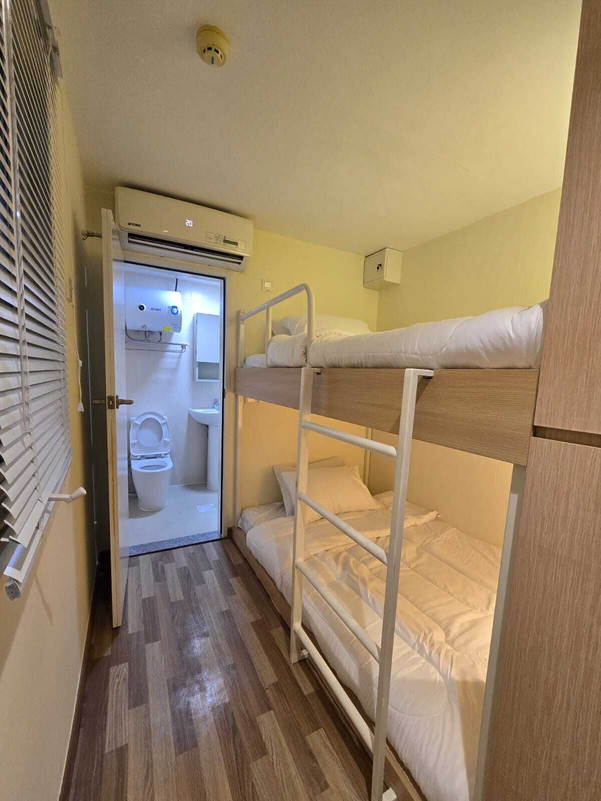 A compact room with bunk beds, a toilet, and a small kitchenette.