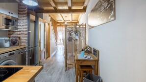 Une cuisine avec un mur en briques, un plafond en bois et un coin repas comprenant une table et des chaises.