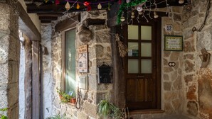 Un bâtiment en pierre avec une porte en bois, des plantes en pot et une enseigne indiquant un restaurant.