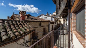 Un bâtiment traditionnel avec un toit en tuiles, un balcon doté d’une rambarde en métal et un ciel d’un bleu éclatant.