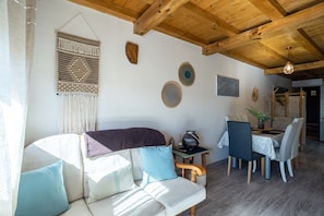Una sala de estar acogedora con sofá, mesa de comedor y vigas de madera en el techo.