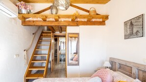 Une chambre avec un escalier en bois, un lit avec une literie à motifs et un tableau accroché au mur.