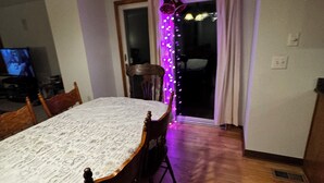 A dining area with a table covered in a patterned tablecloth, wooden chairs, and a ceiling light fixture. -  4-bedroom house in Dublin close to ,zoo shopping,restaurant,airport ,5 star (Dublin)