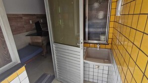 Ein Badezimmer mit gelb gefliesten Wänden, einem Waschbecken und einem Fenster.