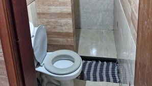 Ein kleines Badezimmer mit Toilette, Dusche und gefliesten Wänden.
