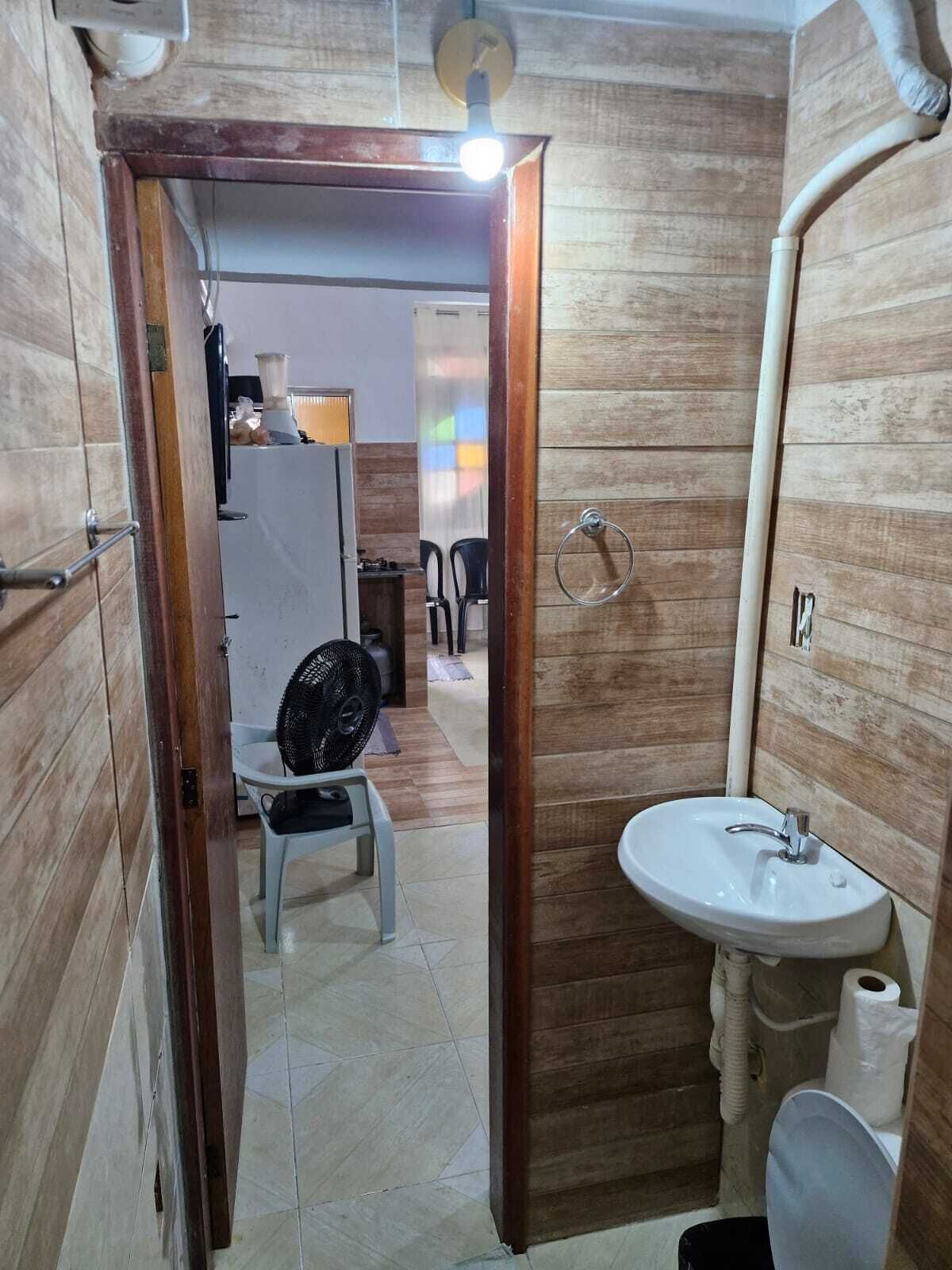 A compact bathroom with a wooden wall, a white sink, and a toilet.