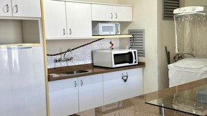 A compact kitchen with white cabinets, a microwave, and a glass-top island. - Apartamento 201 Saint Sebastian Flat (Jaraguá do Sul)