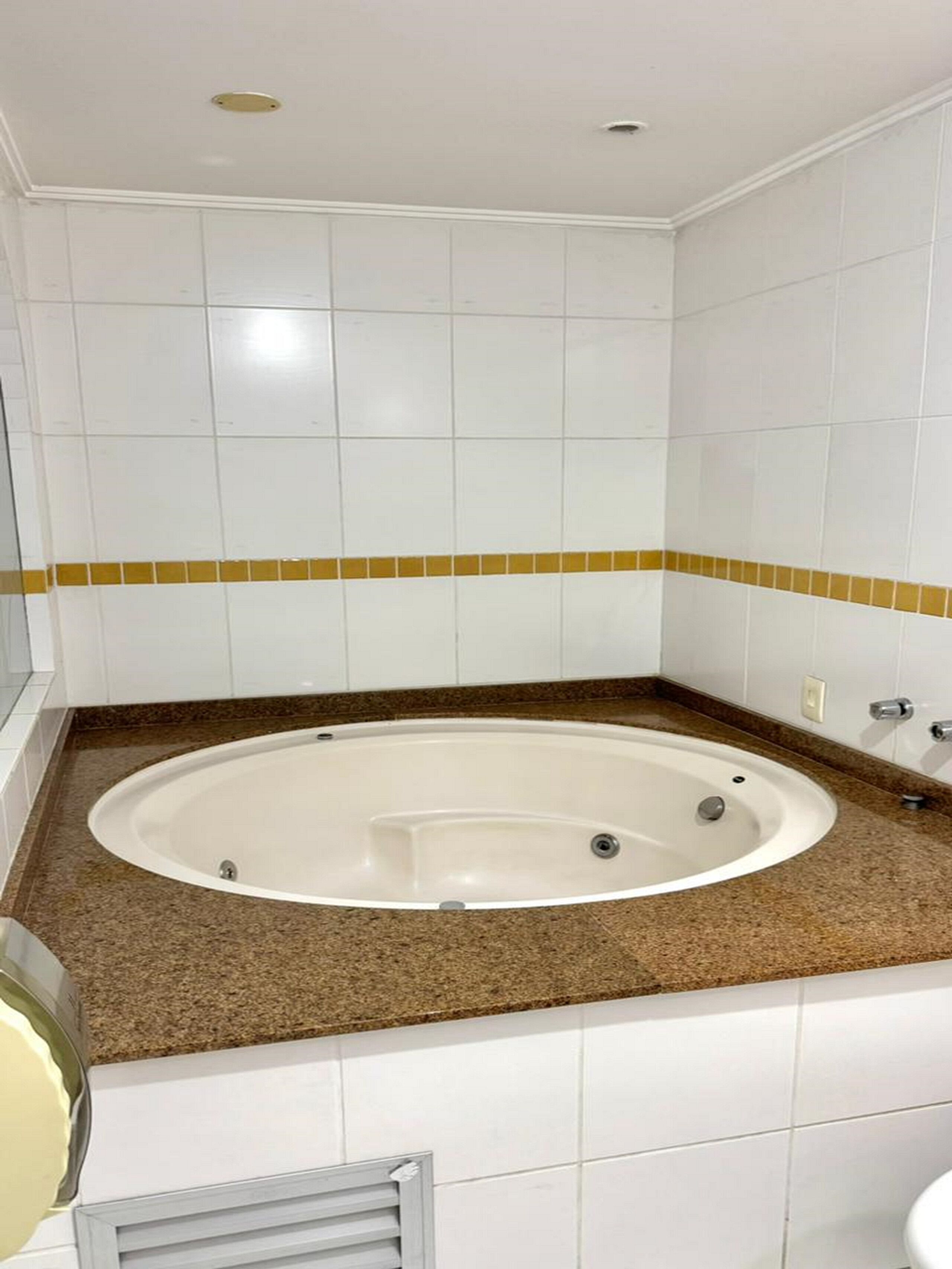 Un baño con una bañera independiente, azulejos blancos y una encimera marrón.